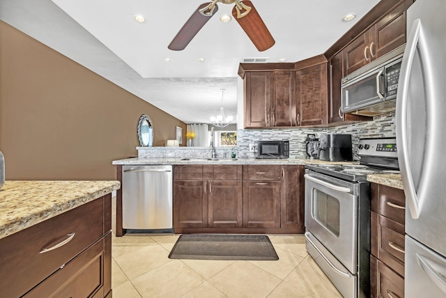 kitchen featuring light tile patterned floors, light stone countertops, appliances with stainless steel finishes, and sink