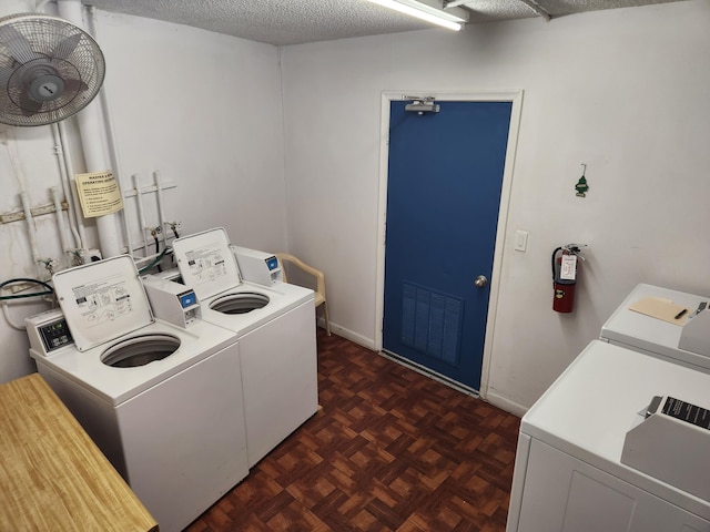 laundry area featuring separate washer and dryer, a textured ceiling, and dark parquet flooring