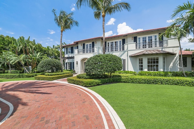 view of front of home with a balcony and a front lawn