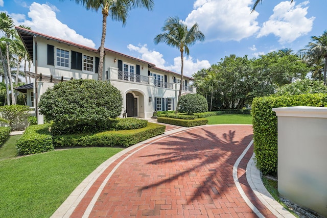 view of front of property featuring a balcony and a front lawn