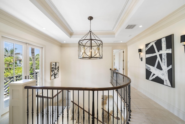 corridor with crown molding, a notable chandelier, light tile patterned floors, and a tray ceiling