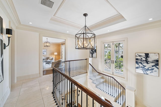 hallway with light tile patterned flooring, ornamental molding, a notable chandelier, and a raised ceiling