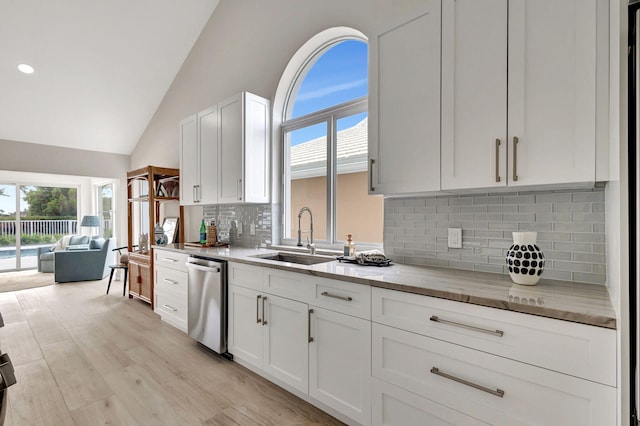 kitchen with sink, light hardwood / wood-style flooring, dishwasher, white cabinets, and decorative backsplash