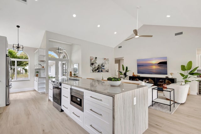 kitchen featuring a kitchen island, appliances with stainless steel finishes, decorative light fixtures, white cabinets, and light stone counters