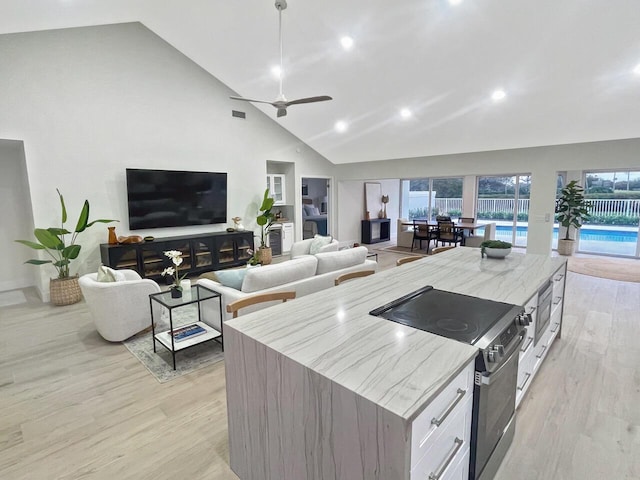 kitchen with pendant lighting, stainless steel electric stove, white cabinets, and light hardwood / wood-style flooring