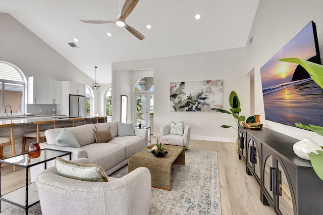 living room featuring ceiling fan, sink, high vaulted ceiling, and light hardwood / wood-style flooring