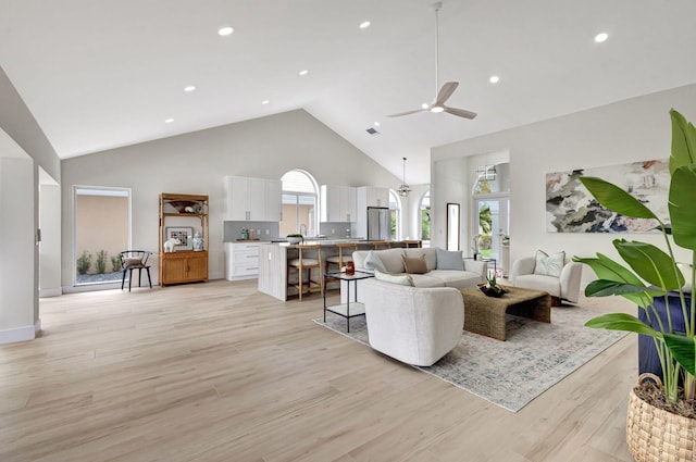 living room featuring ceiling fan, high vaulted ceiling, and light hardwood / wood-style flooring