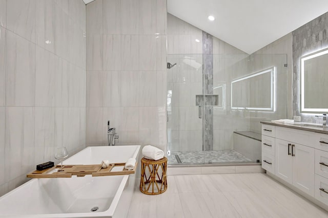 bathroom with vanity, shower with separate bathtub, vaulted ceiling, and tile walls