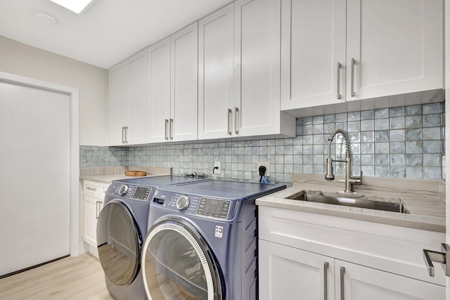 clothes washing area featuring light hardwood / wood-style floors, cabinets, separate washer and dryer, and sink