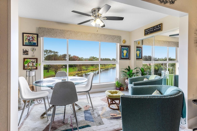 sunroom featuring a water view and ceiling fan