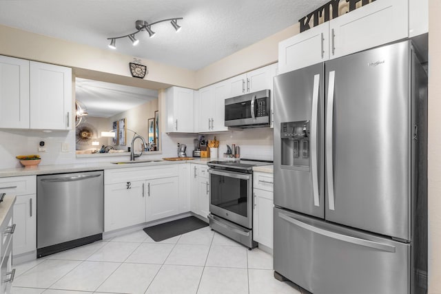 kitchen with tasteful backsplash, sink, white cabinets, stainless steel appliances, and a textured ceiling