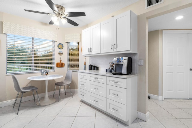 kitchen with white cabinetry, light tile patterned floors, ceiling fan, and decorative backsplash