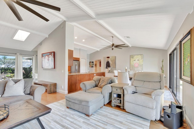 living room featuring lofted ceiling with skylight, ceiling fan, and light wood-type flooring