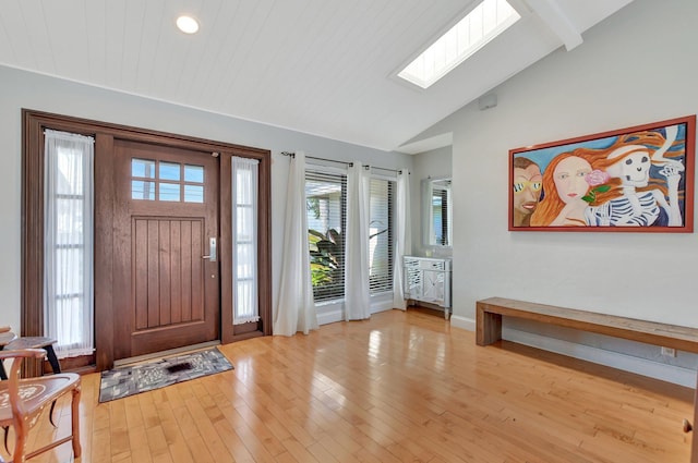 foyer with vaulted ceiling with skylight and light hardwood / wood-style floors