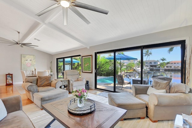 living room featuring a water view, ceiling fan, light hardwood / wood-style floors, and vaulted ceiling with beams