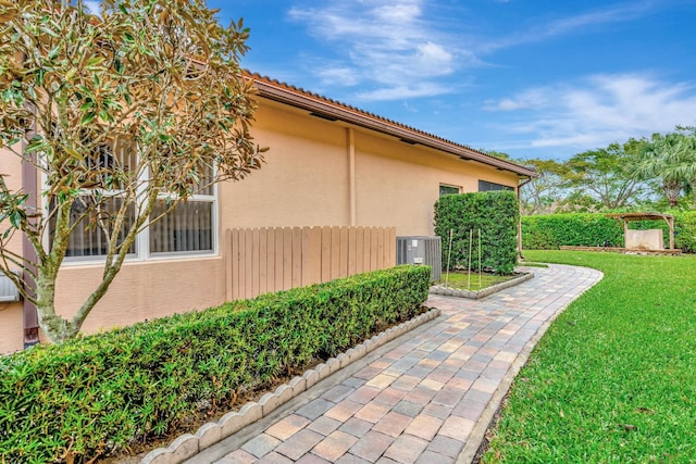 view of side of home featuring central AC and a yard