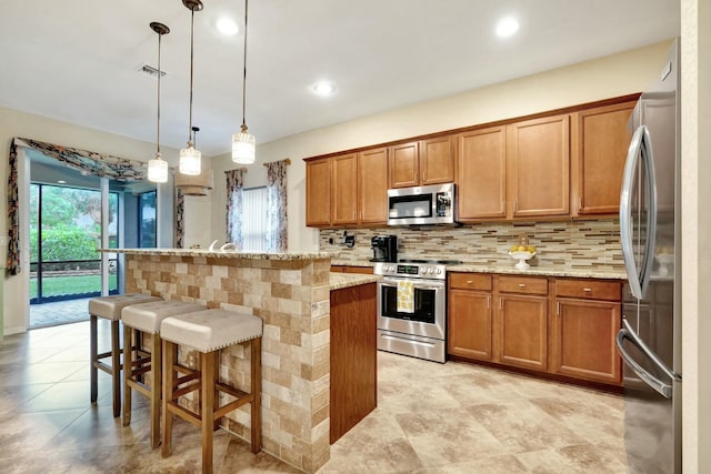 kitchen featuring a center island, decorative light fixtures, a kitchen bar, stainless steel appliances, and light stone counters