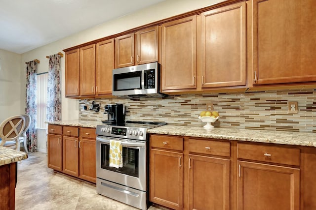 kitchen featuring light stone counters, decorative backsplash, and appliances with stainless steel finishes