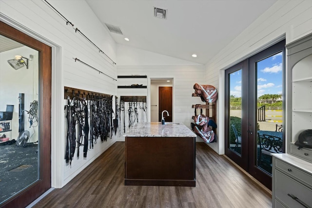 interior space with light stone countertops, sink, a center island with sink, and dark wood-type flooring