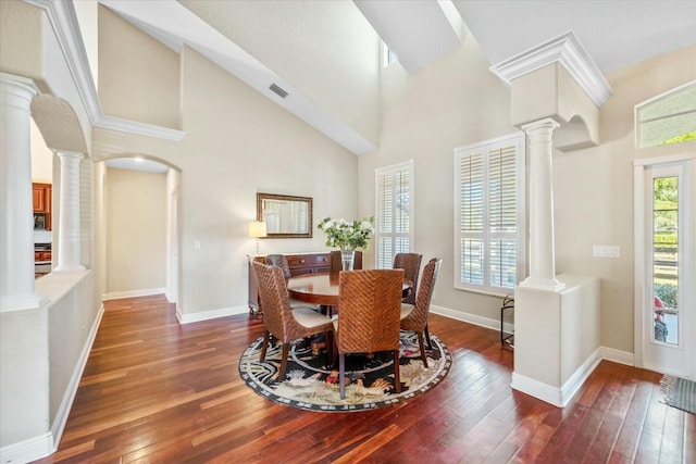 dining room featuring dark hardwood / wood-style flooring, a healthy amount of sunlight, and ornate columns