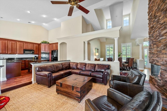 living room featuring ceiling fan, high vaulted ceiling, light hardwood / wood-style floors, and ornate columns