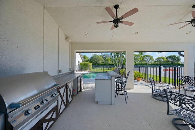 view of patio with an outdoor kitchen, grilling area, ceiling fan, and an outdoor wet bar