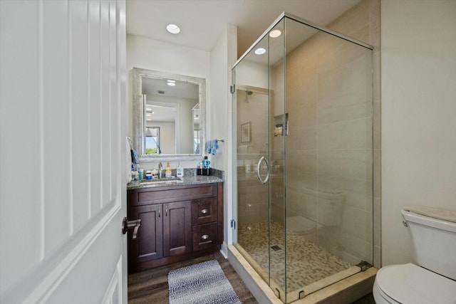 bathroom with hardwood / wood-style flooring, vanity, toilet, and a shower with shower door