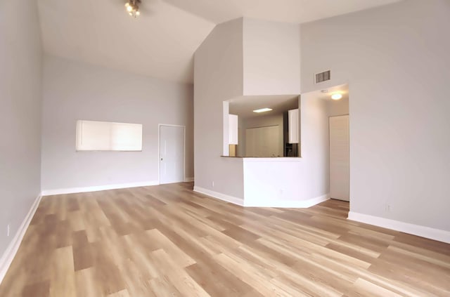 unfurnished living room with high vaulted ceiling and light hardwood / wood-style floors