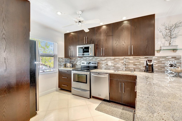 kitchen featuring sink, light tile patterned floors, light stone countertops, and appliances with stainless steel finishes