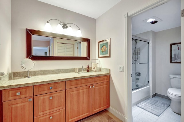 full bathroom featuring vanity, tile patterned flooring, combined bath / shower with glass door, and toilet