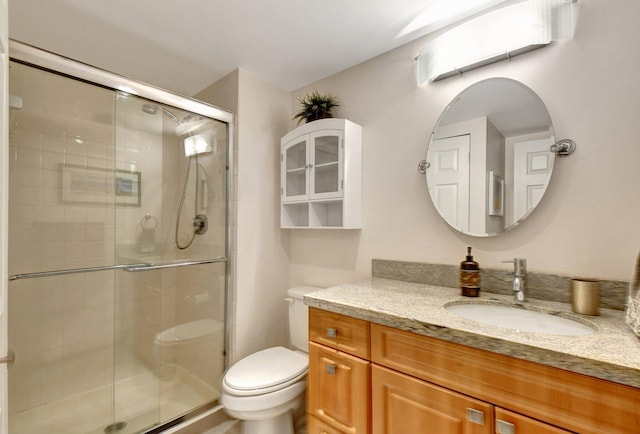 bathroom with vanity, a shower with door, and toilet