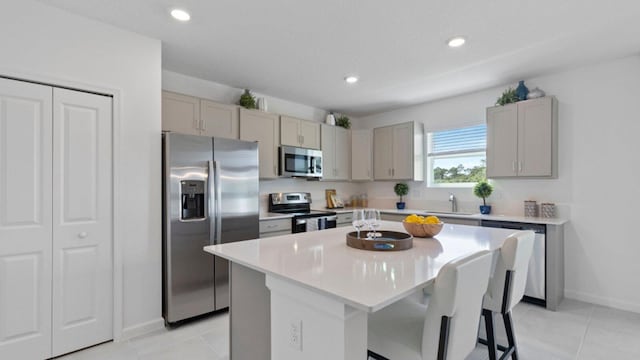 kitchen featuring light countertops, stainless steel appliances, a sink, and a center island