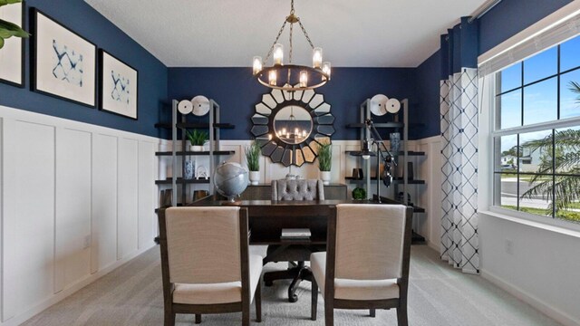 dining room with a chandelier, a wainscoted wall, and light carpet