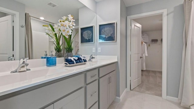 bathroom with double vanity, visible vents, a sink, and tile patterned floors