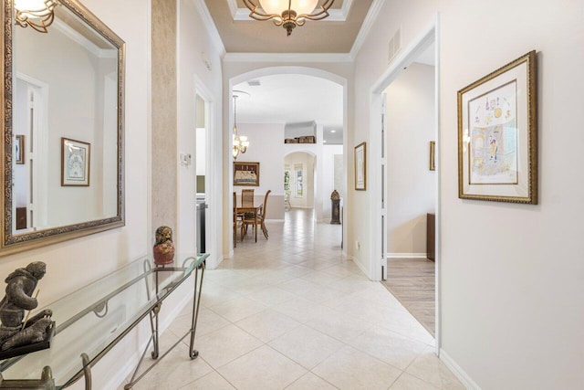 hall featuring light tile patterned floors, crown molding, and a chandelier