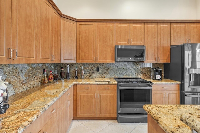 kitchen with light stone countertops, stainless steel appliances, light tile patterned floors, and decorative backsplash