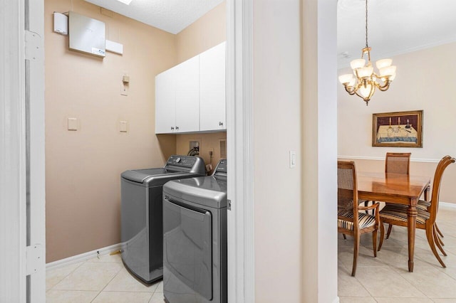 laundry room featuring washing machine and dryer, an inviting chandelier, cabinets, and light tile patterned flooring