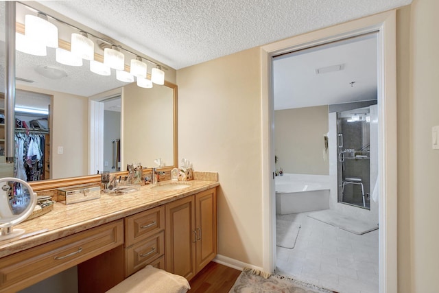 bathroom featuring hardwood / wood-style flooring, vanity, a bath, and a textured ceiling