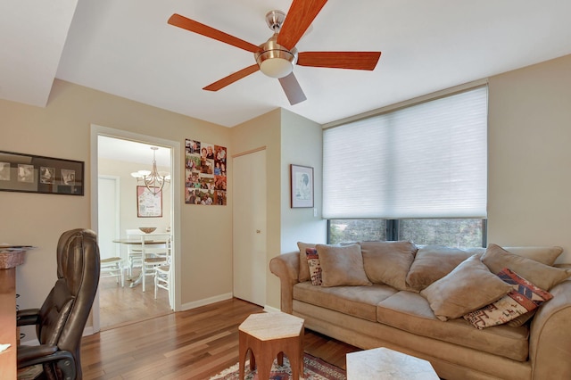 living room featuring ceiling fan with notable chandelier and light hardwood / wood-style flooring