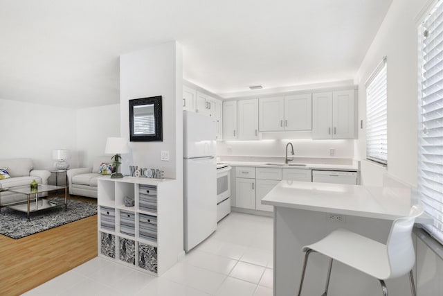 kitchen with sink, white cabinetry, white appliances, and light tile patterned floors