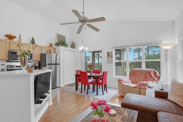 living room featuring ceiling fan with notable chandelier, light hardwood / wood-style flooring, and high vaulted ceiling