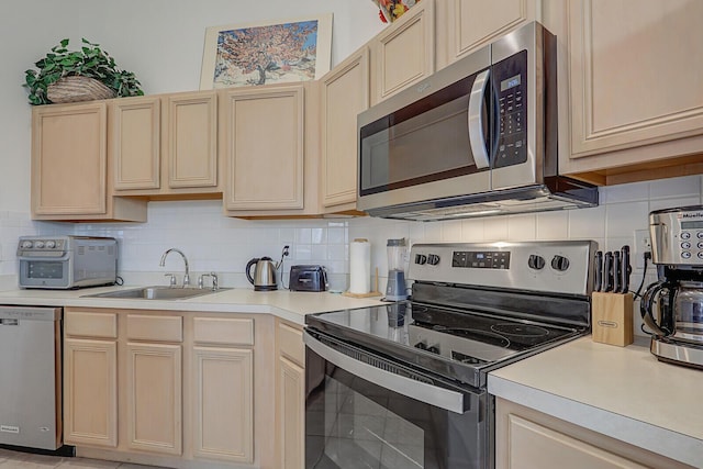 kitchen featuring sink, stainless steel appliances, decorative backsplash, and light brown cabinets