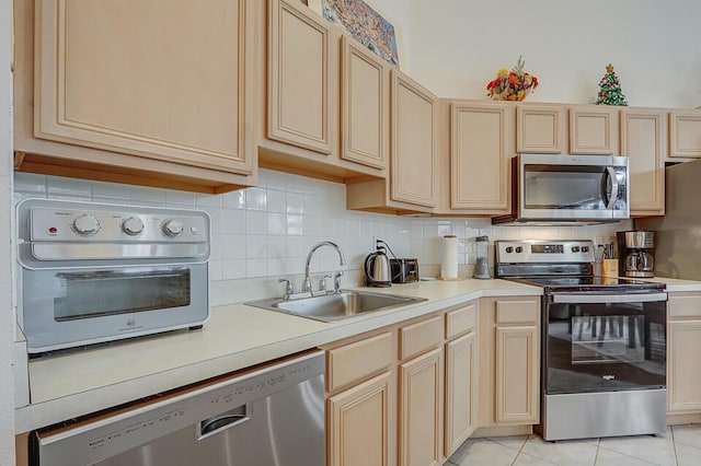 kitchen with light brown cabinetry, appliances with stainless steel finishes, light tile patterned floors, decorative backsplash, and sink