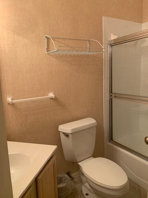 full bathroom with vanity, toilet, bath / shower combo with glass door, and tile patterned flooring