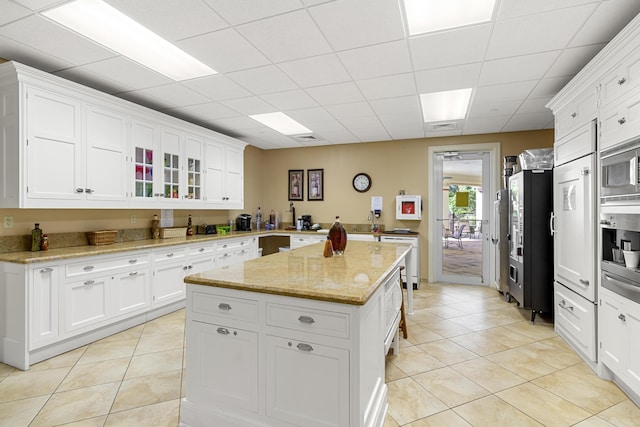 kitchen with light stone counters, white cabinetry, and light tile patterned flooring