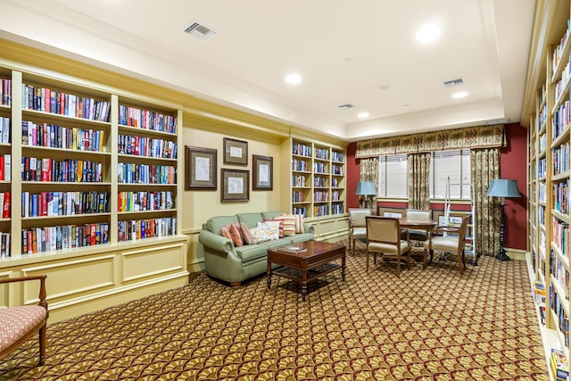 sitting room featuring carpet, a raised ceiling, and crown molding