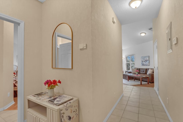 hall with a textured ceiling and light tile patterned flooring