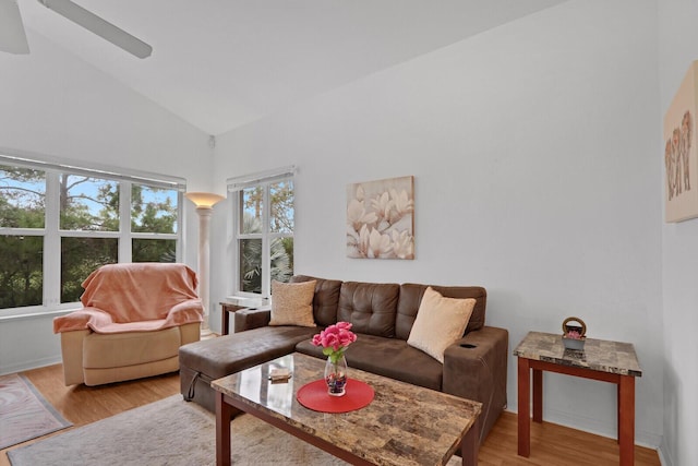 living room with decorative columns, ceiling fan, high vaulted ceiling, and light hardwood / wood-style flooring