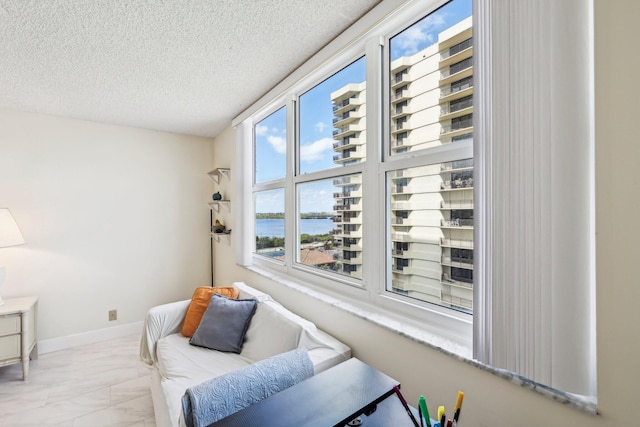 sitting room featuring a water view and a textured ceiling