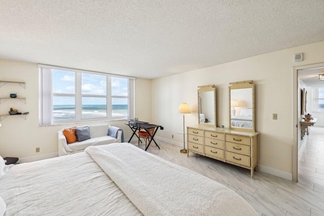 bedroom featuring a water view and a textured ceiling